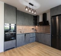 Moderný 2-izbový byt s balkónom, Ovocné sady - Kuchyňa v 2-izbovom byte s antracitovými skriňami a podlahou s dreveným dekorom.