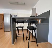 Prenájom 2 izbový 78 m2 + 30 m2 terasa,novostavba Koliba,zariadený - Kuchyňa 2-izbového bytu s barovým pultom, stoličkami a podlahou s dreveným dekorom.