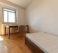 Zariadený 4-izbový byt s balkónmi a parkovaním - Izba s posteľou, stolom a podlahou s dreveným dekorom v 4-izbovom byte.