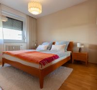 Zariadený 4-izbový byt s balkónmi a parkovaním - Spálňa s manželskou posteľou, nočným stolíkom a podlahou s dreveným dekorom v 4-izbovom byte.