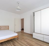 Renovovaný 3-izbový byt, Ružinov - Spálňa s drevenou posteľou, bielou skriňou a podlahou s dreveným dekorom v 3-izbovom byte.
