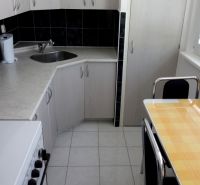 2-izbový byt, 51 m², samostatné izby, tichý, výhľad do zelene,K.Adlera - Kuchyňa 2-izbového bytu s bielymi skrinkami, sporákom a malým stolom.