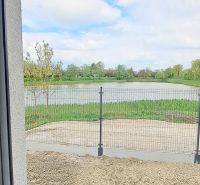 Novostavba pri jazere - 4 izbový rodinný dom v štandarde v obci Selice - Výhľad z rodinného domu v Seliciach na zarastenú vodnú plochu a plot.
