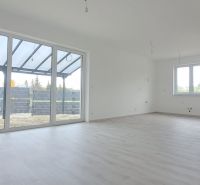 Novostavba pri jazere - 4 izbový rodinný dom v štandarde v obci Selice - Priestranný interiér rodinného domu s veľkými oknami a podlahou s dreveným dekorom.
