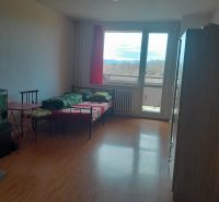 Predaj, Garsónka, Žiar nad Hronom  - Garsónka s pohovkou, podlahou s dreveným dekorom a výhľadom cez veľké okno.