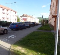 Predaj, 2 - izbový byt, Žiar nad Hronom - Parkovisko a budovy pri ceste v Žiari nad Hronom neďaleko 2-izbového bytu.
