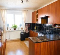 Predaj, 2 - izbový byt, Žiar nad Hronom - Kuchyňa v 2-izbovom byte s podlahou s dreveným dekorom a tmavými obkladmi.