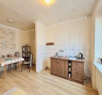 Viacgeneračný RD - priestranný pozemok - vyhľadávaná lokalita - Kuchyňa v rodinnom dome s podlahou s dreveným dekorom a jedálenským stolom.