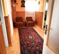 Priestranný 6-izbový rodinný dom v srdci Vysokej nad Kysucou – komfort - Rodinný dom so starožitným kobercom, podlahou s dreveným dekorom a oranžovými stenami.