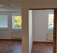 NA PREDAJ – polyfunkčný objekt v úplnom centre mesta Senec - obchodný  - Interiér rodinného domu s terakotovou podlahou, bielymi stenami a radiátormi pod oknami.