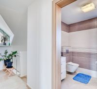 REZERVOVANÉ 5-izbový rodinný dom Hrnčiarovce - Kúpeľňa v rodinnom dome s rastlinami, dlažbou a práčkou, svetlé a elegantné prostredie.