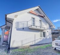 REZERVOVANÉ 5-izbový rodinný dom Hrnčiarovce - Rodinný dom v Hrnčiarovciach nad Parnou s bielou fasádou a balkónom na kamienkovom dvore.