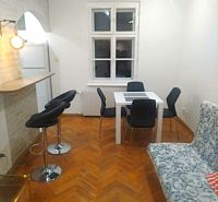 Prenájom 2 izbový byt, Murgašova ulica, Bratislava I. Staré Mesto - Jedálenský kút s bielym stolom, sivými stoličkami a podlahou s dreveným dekorom v 2-izbovom byte.