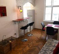 Prenájom 2 izbový byt, Murgašova ulica, Bratislava I. Staré Mesto - Obývacia izba 2-izbového bytu s podlahou s dreveným dekorom, barom a jedálenským stolom.