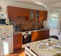 NA PREDAJ celoročná chata – Sekule (Šutrovňa), tiché prostredie - Interiér chaty so staršou kuchynskou linkou, chladničkou a dekoratívnym tanierom na stene.