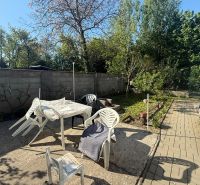 NA PREDAJ celoročná chata – Sekule (Šutrovňa), tiché prostredie - Záhrada chaty v Sekuliach s plastovým nábytkom a stromami po okrajoch.