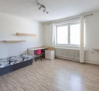 Predaj rodinného domu Piešťany - Izba v rodinnom dome s posteľou, stolom, ružovou stoličkou a podlahou s dreveným dekorom.