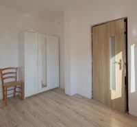 Predaj rodinného domu Piešťany - Izba v rodinnom dome s podlahou s dreveným dekorom, skriňou a stoličkou.