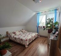 Poschodový rodinný dom v  obci Klokočov okr. Michalovce - Spálňa v rodinnom dome so podlahou s dreveným dekorom a posteľou s kvetinovým prehozom.