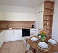 Exkluzívne 2 izbový byt POPRAD Karpatská, s garaž. st., balkón, 58 m2 - Kuchyňa v 2-izbovom byte so stolom a podlahou s dreveným dekorom.