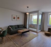 Exkluzívne 2 izbový byt POPRAD Karpatská, s garaž. st., balkón, 58 m2 - Obývačka v 2-izbovom byte s podlahou s dreveným dekorom a presklenou lodžiou.