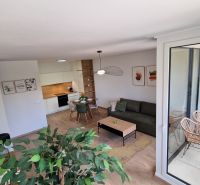 Exkluzívne 2 izbový byt POPRAD Karpatská, s garaž. st., balkón, 58 m2 - Interiér 2-izbového bytu s podlahou s dreveným dekorom, moderným nábytkom a balkónom.