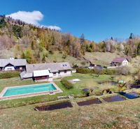 (1.692 m²) RYBIA FARMA S CHATOU V SRDCI PRÍRODY - Exteriér rodinného domu v Hnilčíku s bazénom, stromami a kopcovitou krajinou.