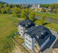 Na predaj 4iz. byt na Banke pri Piešťanoch - Bytový dom s čiernou strechou pri rieke na Moravanskej ulici v Banke.
