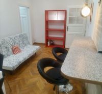 – PRENAJOM – 2 IZBOVÝ – MURGAŠOVA – STARE MESTO  - Obývacia izba s barovým pultom, sedačkou a regálmi v 2-izbovom byte s podlahou s dreveným dekorom.