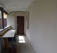 Domček na chalupárčenie s veľkým pozemkom s termál kúpaliskom v obci! - Chodba s bielymi stenami, praskliny na podlahe, stôl, dvere v rodinnom dome.