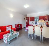 Brač(HR) - Apartmány v 1. rade u mora !!! - Rekreačný apartmán s červenou sedacou súpravou a kuchyňou s jedálenským kútom.