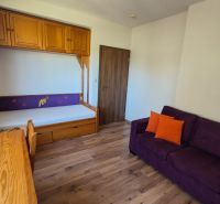 Investičný apartmán Vysoké Tatry - Stará Lesná s balkónom a park.miest - Rekreačný apartmán s pohovkou, posteľou, skriňou a podlahou s dreveným dekorom.