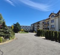 Investičný apartmán Vysoké Tatry - Stará Lesná s balkónom a park.miest - Zeleň v okolí rekreačných apartmánov na Starej Lesnej vo Vysokých Tatrách pod modrou oblohou.