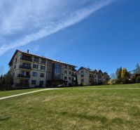 Investičný apartmán Vysoké Tatry - Stará Lesná s balkónom a park.miest - Rekreačný apartmán v Staréj Lesnej vo Vysokých Tatrách, obklopený trávnikom a stromami.