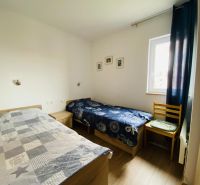 Brač(HR)–Apartmán s výhľadom na more - Dve postele, stolička, okno, obrazy na stenách, podlaha s dreveným dekorom.