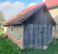 EXKLUZÍVNE NA PREDAJ – pekný pozemok na stavbu domu alebo chaty BUDINÁ - Stará drevená garáž na pozemku pre bývanie v Budinej, obklopená zeleňou a stromami.
