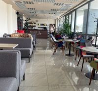 ODSTÚPENIE ZABEHNUTEJ KAVIARNE V CENTRE TRNAVY – TROJIČNÉ NÁMESTIE - Moderný interiér kaviarne s pohodlnými sedadlami a veľkými oknami.