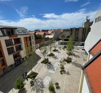 ODSTÚPENIE ZABEHNUTEJ KAVIARNE V CENTRE TRNAVY – TROJIČNÉ NÁMESTIE - Výhľad na Trojičné námestie v Trnave, s gastro priestormi a zeleňou.