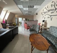 ODSTÚPENIE ZABEHNUTEJ KAVIARNE V CENTRE TRNAVY – TROJIČNÉ NÁMESTIE - Gastro priestory s podlahou s dreveným dekorom, kreslami a stenou s dekoráciou.