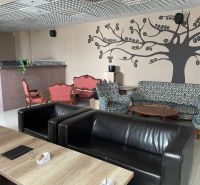 ODSTÚPENIE ZABEHNUTEJ KAVIARNE V CENTRE TRNAVY – TROJIČNÉ NÁMESTIE - Gastro priestory s koženými kreslami, vzorovanými sedačkami a dekoráciami na stene.