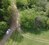 Pozemok vhodný na chov včiel Streženice- 874 m2 - Žena stojí pred rekreačnými pozemkami v Streženiciach, ideálnymi pre chov včiel.