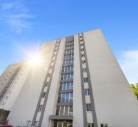 2-izbový byt po rekonštrukcii v Starom Meste na predaj  - Výšková bytovka v Bratislave - Starom Meste s modrou oblohou a parkoviskom.