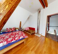 Na predaj rodinný dom v obci Malé Chlievany - Podkrovná izba v rodinnom dome s posteľou, dekoračným drevom a podlahou s dreveným dekorom.
