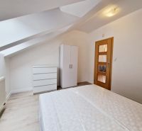 3 IZBOVÝ BYT NA PRENÁJOM PREŠOV, PUSTÁ DOLINA, ŠIDLOVEC - Podkrovná spálňa v 3-izbovom byte s bielym nábytkom a podlahou s dreveným dekorom.