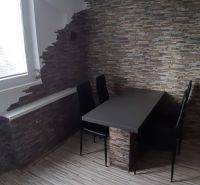 Na prenájom 2-izbový byt - Nové Zámky - Jedálenský kút so stolom a stoličkami v 2-izbovom byte, stena z kameňa.