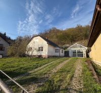 RODINNÝ DOM V PRÍRODE - NA PREDAJ -OBEC ŠTÓS  - Rodinný dom v Štóse obklopený zeleňou a drevenou konštrukciou prístrešku.
