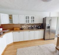 Predaj, rodinný dom Vitanová - EXKLUZÍVNE HALO REALITY - Kuchyňa v rodinnom dome s bielymi skrinkami, chladničkou a podlahou s dreveným dekorom.