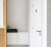 *Prenájom obchodného priestoru s výkladom, 26,3 m² – Račianske mýto* - Biely interiér obchodných priestorov s umývadlom a dverami.