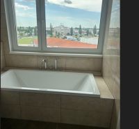 PREDAJ NADŠTANDARDNÉHO 4 IZB.BYTU V NOVOM KOMPLEXE-VINICE-150,18 m2 - Kúpeľňa v 4-izbovom byte s vaňou a výhľadom na mesto.