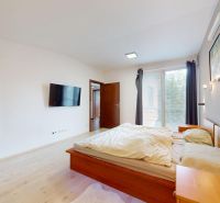 5-izbový dom 170m² + pozemok 529m² | Podunajské Biskupice - Spálňa s posteľou, televízorom a podlahou s dreveným dekorom.